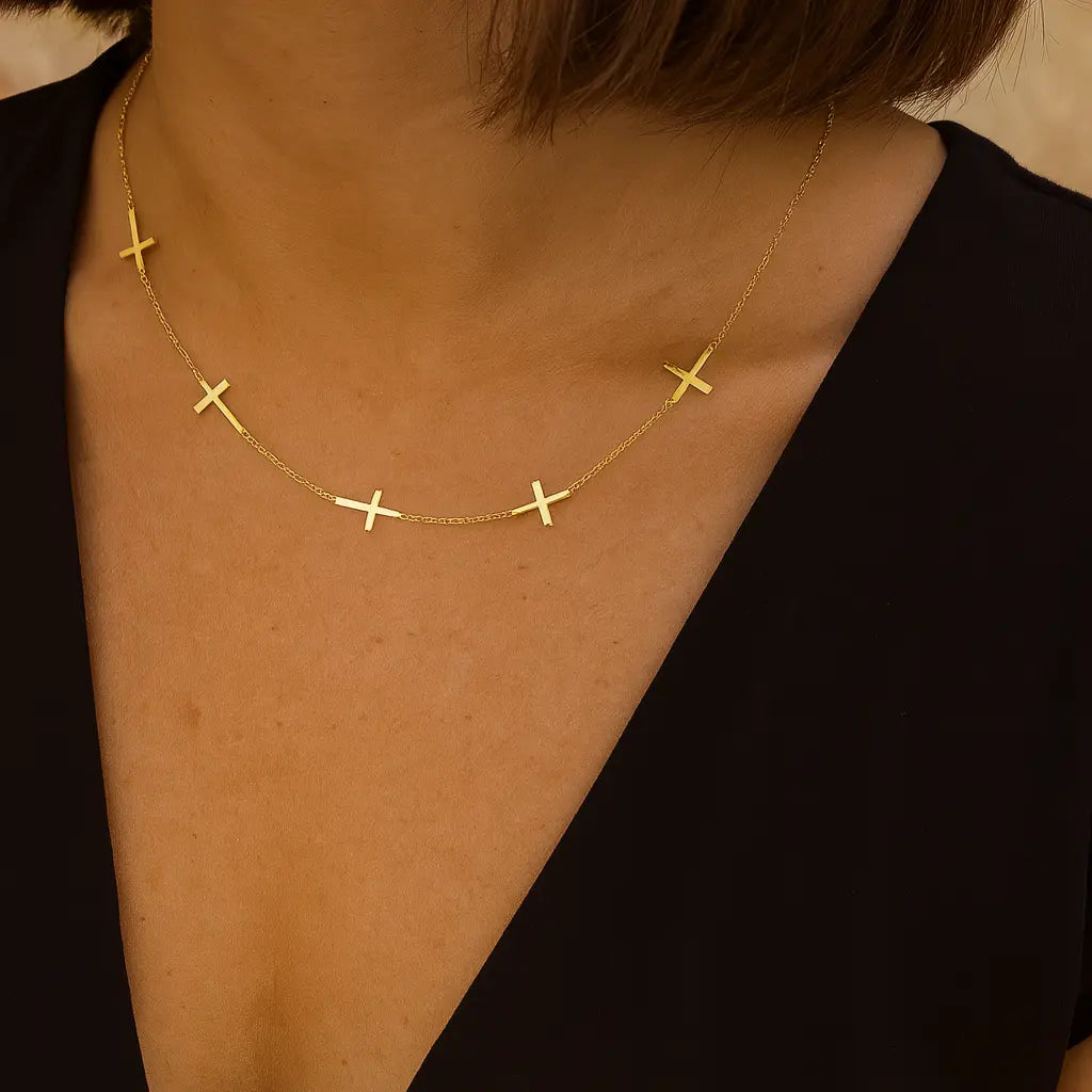 Gold cross necklace on a person wearing a black top