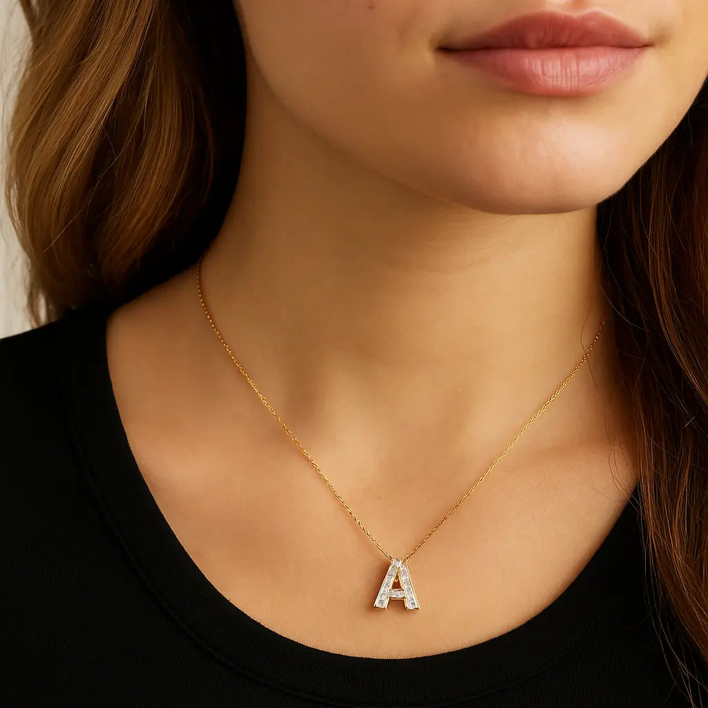 Close-up of a person wearing a gold necklace with a 'A' pendant.